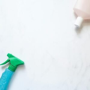 Flat lay of cleaning spray and bottle on a white surface with ample copy space.